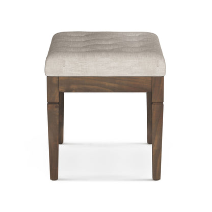 The Waverly Upholstered Tufted Ottoman Bench features a square wooden frame with four legs and a padded, light beige tufted seat, displayed from the front on a white background.