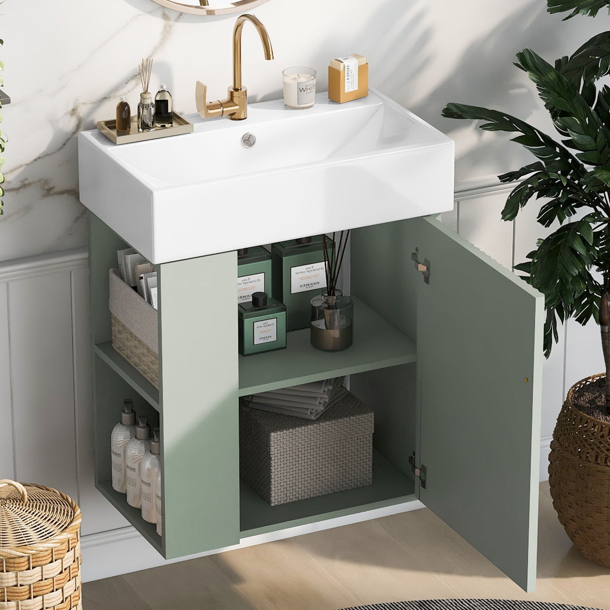 The Modern Floating Bathroom Vanity With Ceramic Basin, ideal for small bathrooms, features a gold faucet and open light green cabinets displaying organized baskets, bottles, towels, and toiletries. A plant and wicker basket add a stylish touch nearby.