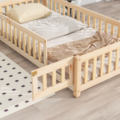 The House-Shaped Headboard Floor Bed With Fence features light wood, railings, a small gate (shown open), a beige blanket, and a cream pillow. It's placed on a light wood floor beside a white rug with black squares.