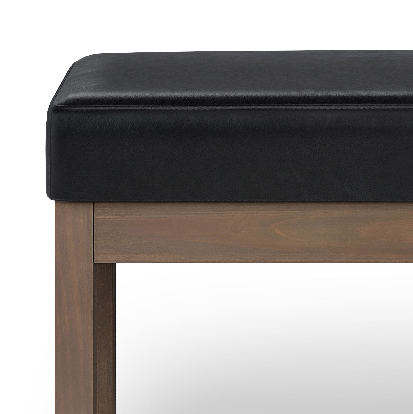 A close-up of the Milltown - Upholstered Ottoman Bench, featuring a black cushioned seat and wooden legs, set against a plain white background.