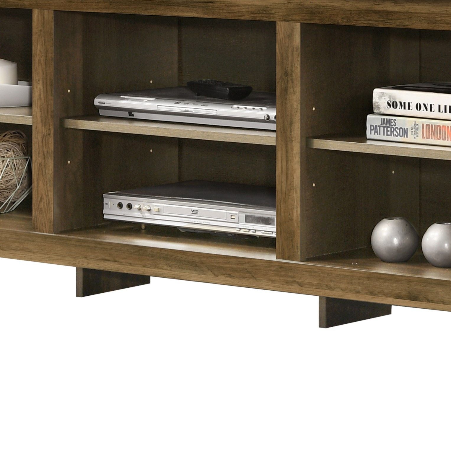 A close-up of the Benito TV Stand with open shelves, featuring electronic devices, a remote control, a book, two round decor pieces, and a wicker basket.