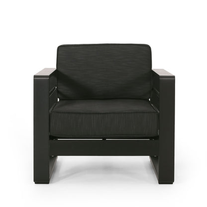 The Maya Bay - Club Chair is a modern black armchair featuring wide armrests, a thick cushioned seat, and a matching cushioned backrest, displayed against a white background.
