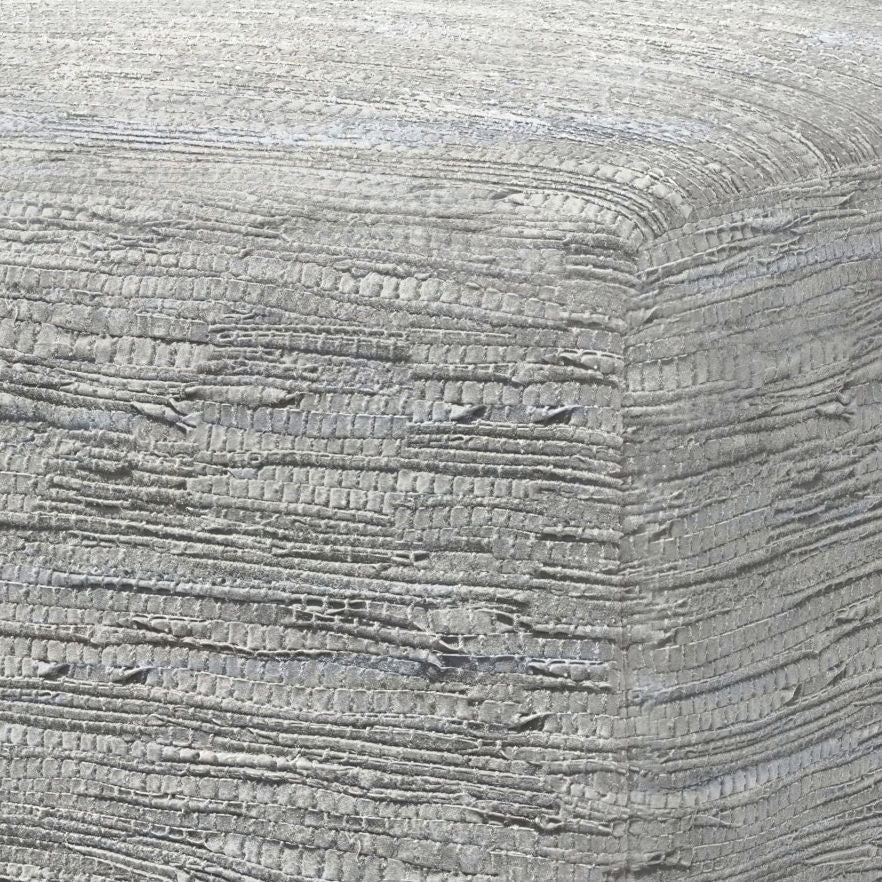 Close-up of the textured, light gray woven fabric covering the corner of the Fredrik - Handcrafted Square Pouf, showcasing its layered and slightly rough pattern.