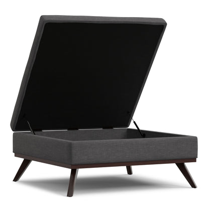 The Owen Multifunctional Square Coffee Table Storage Ottoman features dark fabric upholstery, angled wooden legs, and a hinged lid that opens to reveal roomy storage space inside.