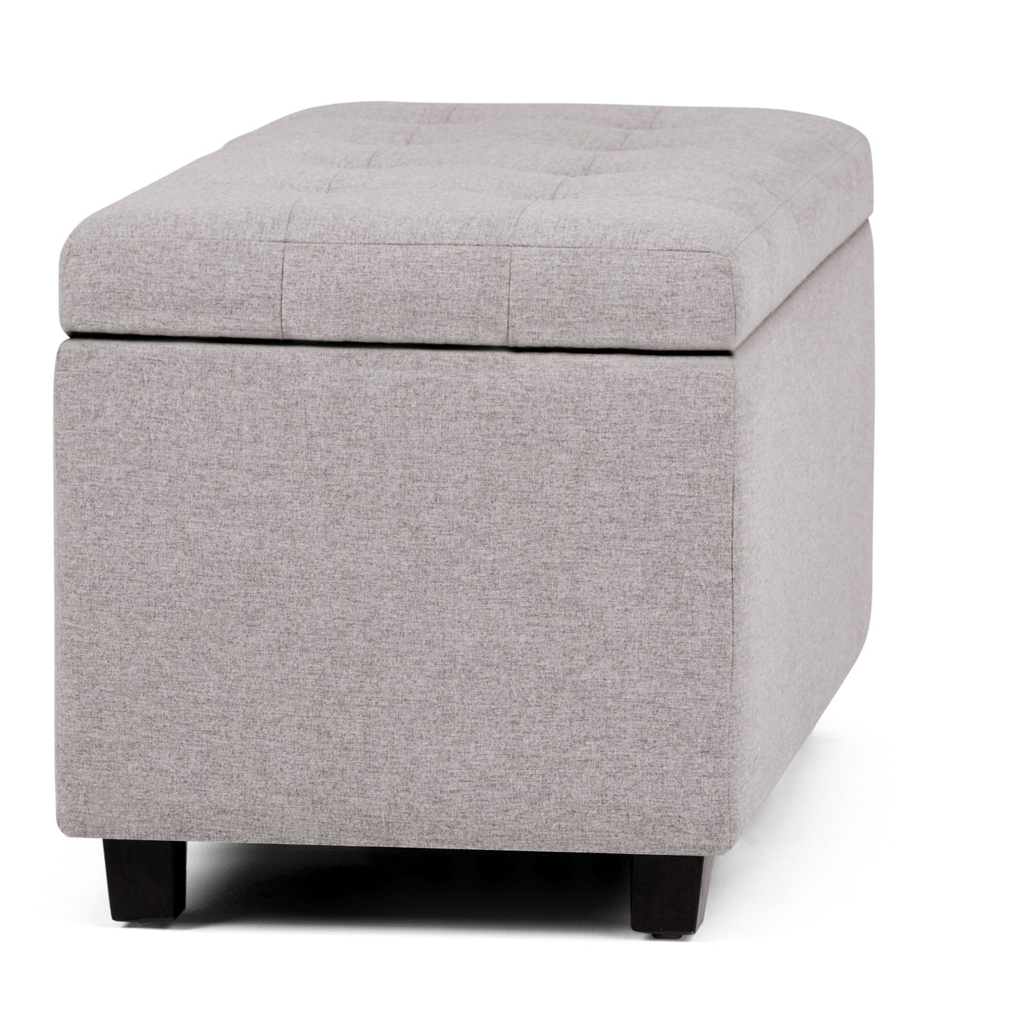 The Cosmopolitan Upholstered Storage Ottoman features light gray fabric, a padded tufted lid, short black legs, and a hollow storage space visible with the lid slightly open.