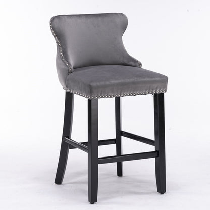 A set of 2 contemporary velvet wing-back barstools with button tufting, chrome nailhead trim, and wooden legs, shown against a plain white background.