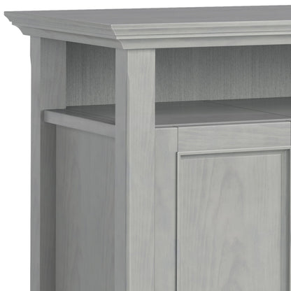 Close-up of the top corner of the Amherst - TV Media Stand, Handcrafted, showcasing its light gray finish, decorative trim, vertical paneling, and open shelf above the cabinet door.