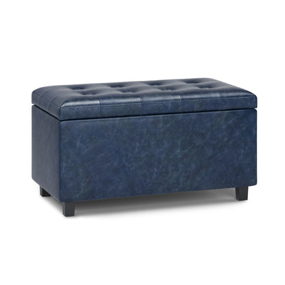 The Cosmopolitan - Upholstered Storage Ottoman is a rectangular, navy blue tufted piece featuring short black legs and a hinged lid for convenient storage.