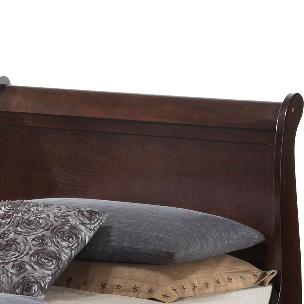 The Louis Phillipe - Storage Bed features a dark wooden sleigh-style headboard with a brown finish, partially visible behind stacked pillows and bedding in gray, floral, and beige patterns.