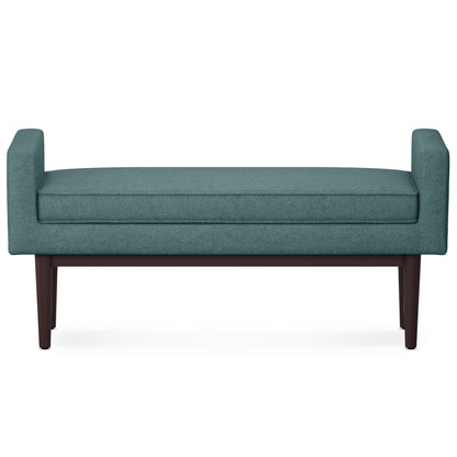 The Scott Upholstered Ottoman Bench features teal fabric, low armrests on both sides, and dark wooden legs, displayed against a white background.