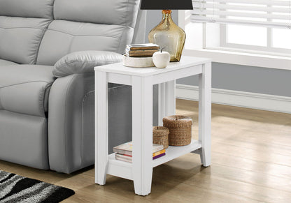 An Accent Table, Side Transitional with an elegant design sits by a gray sofa on wood floors, topped with a lamp, books, and decor. Woven baskets and a book rest on its lower shelf. Nearby is a window fitted with blinds.