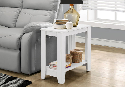 An Accent Table, Side Transitional with an elegant design sits by a gray sofa on wood floors, topped with a lamp, books, and decor. Woven baskets and a book rest on its lower shelf. Nearby is a window fitted with blinds.