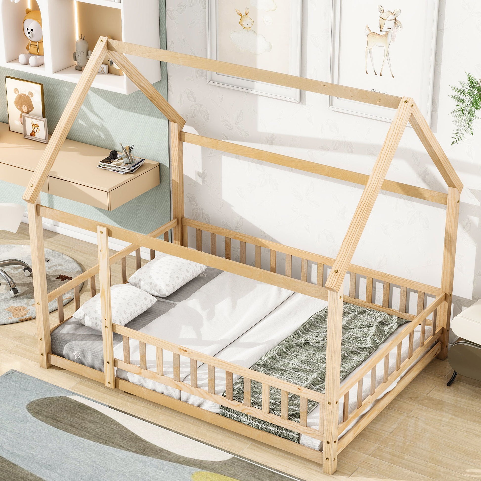 The Floor Wooden Bed With House Roof Frame and Fence Guardrails, dressed in white bedding with a green blanket, is placed in a bright, cozy kids' room decorated with animal artwork and soft toys.