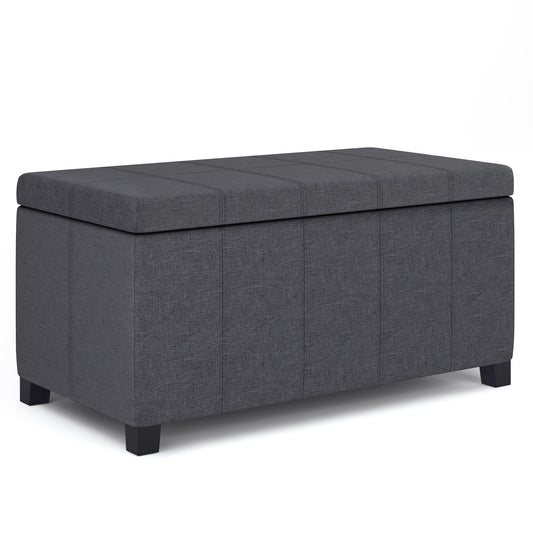 The Dover Upholstered Storage Ottoman Bench is a rectangular, dark gray ottoman with short black legs, a cushioned lid, subtle vertical seams, and hidden storage.