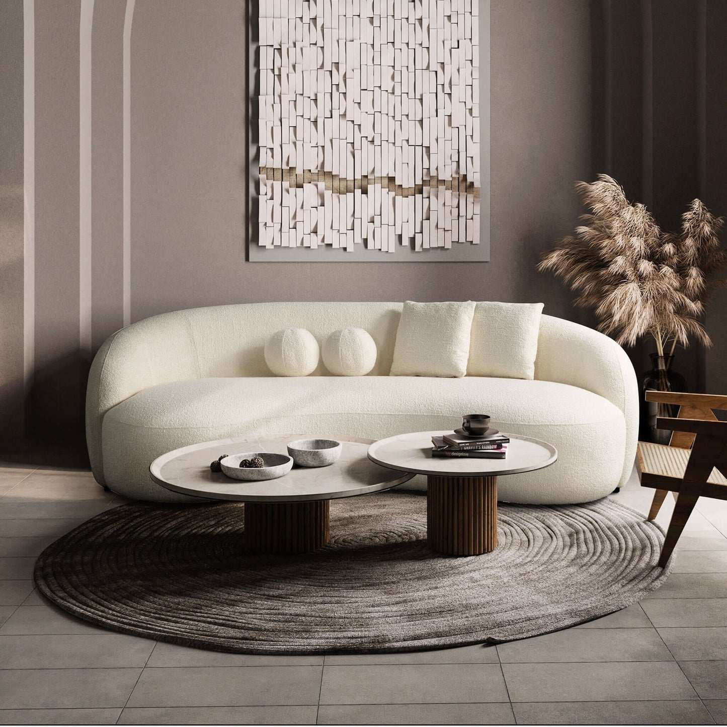 A modern living room features the Drake - Japandi Style Curvy Boucle Sofa, round white coffee tables on a circular rug, beige pampas grass in a vase, and textured wall art. The minimalist décor is finished in neutral tones.