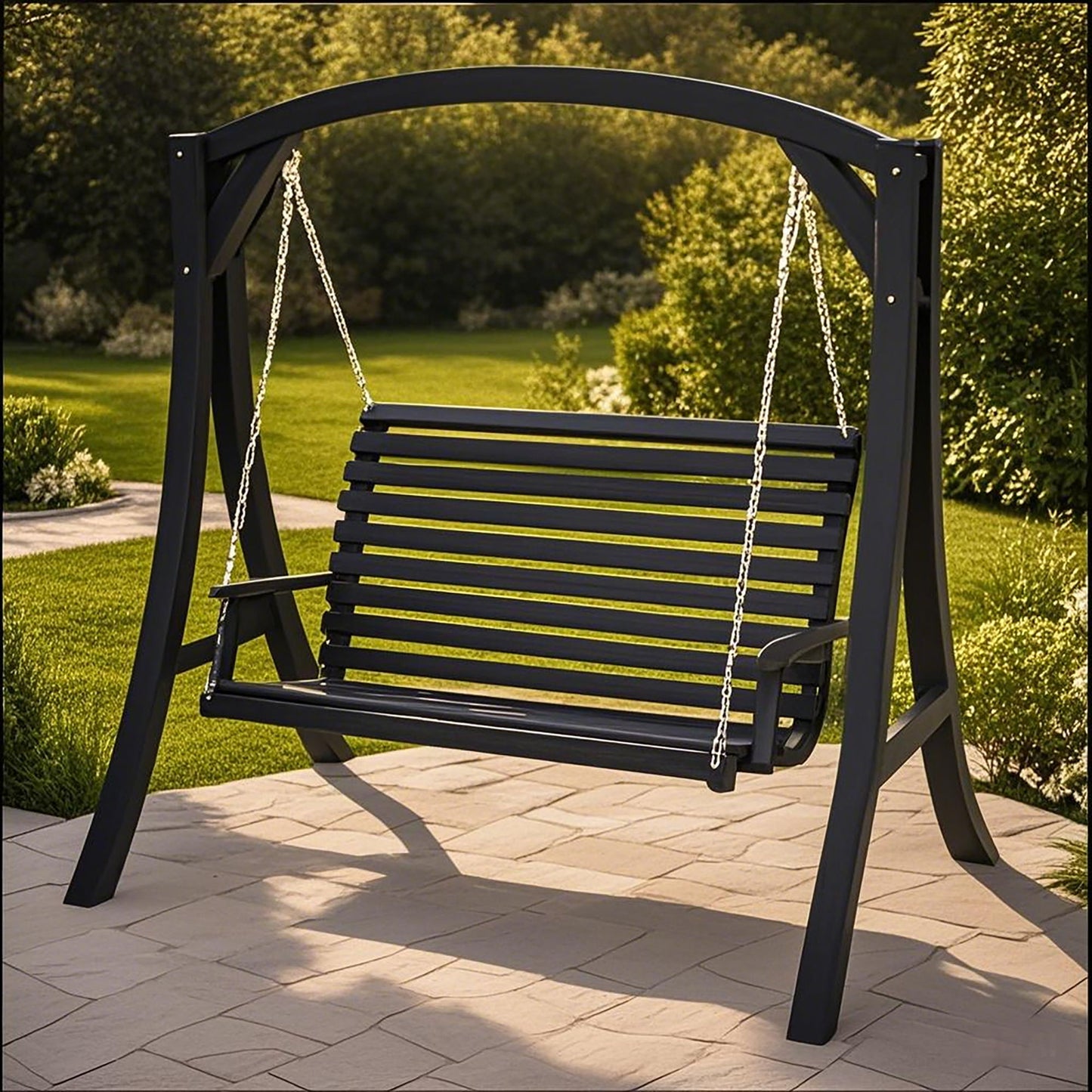 The San Juan Outdoor Swinging Loveseat With Support, made of black wood and metal chains, hangs from a sturdy frame on a stone patio, with green grass and trees in the background.