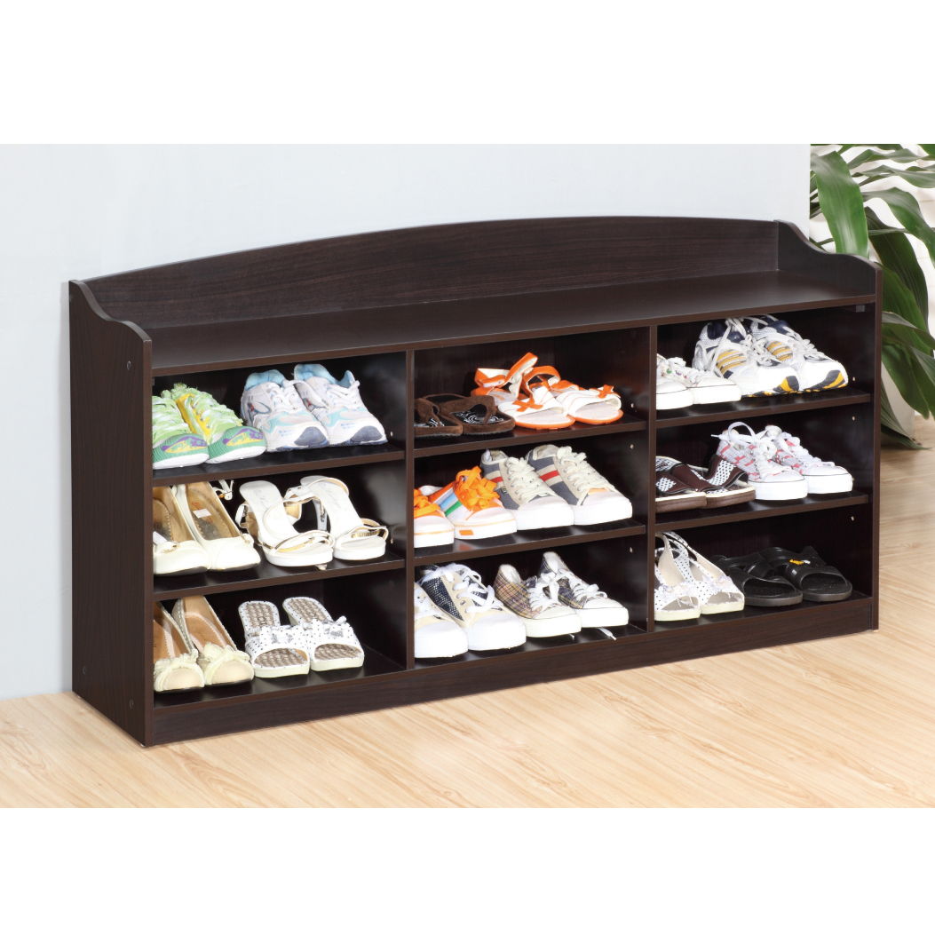 The Entryway Shoe Storage Bench with nine storage shelves is placed against a light wall on a wooden floor, each shelf holding different shoes. A leafy plant appears on the right, adding to the organized entryway look.