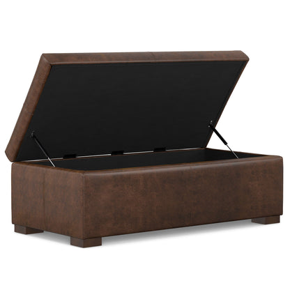 The Gabbie Coffee Table Upholstered Storage Ottoman features a brown leather finish, short legs, and a rectangular shape. Its lid opens to reveal a spacious black interior for storage.