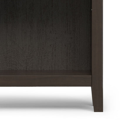 A close-up of the Amherst - 5 Shelf Bookcase in brown, focusing on its legs and bottom shelf against a white background.
