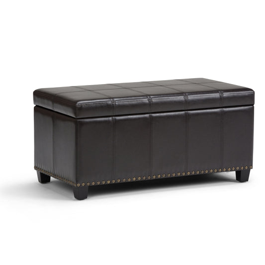 The Amelia - Transitional Storage Ottoman Bench features a rectangular dark brown leather design, short legs, a cushioned top, and decorative metal studs along the bottom edge.
