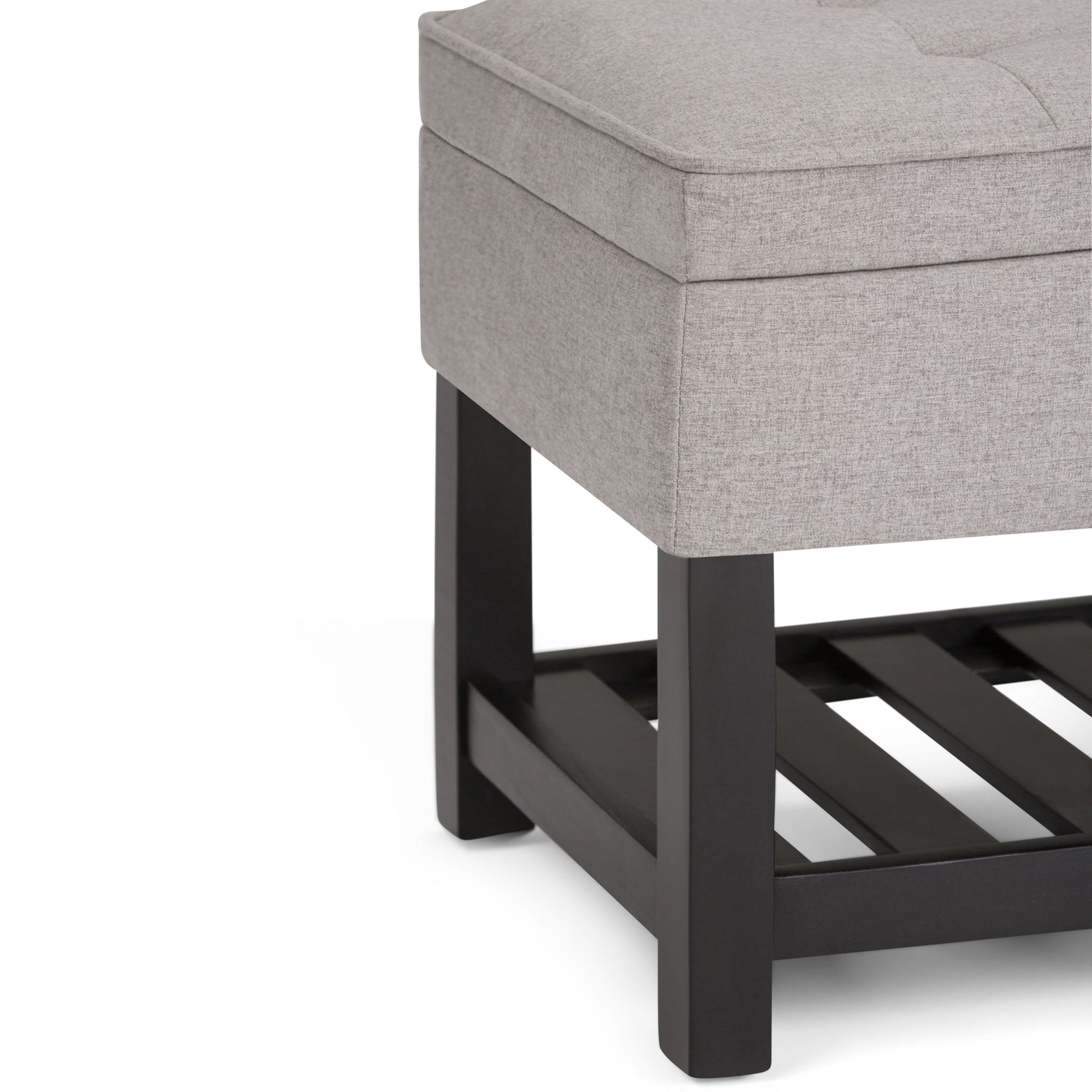 Close-up of the Cosmopolitan Storage Ottoman Bench in light gray upholstery with a cushioned top, dark wood legs, and an open slatted lower shelf.
