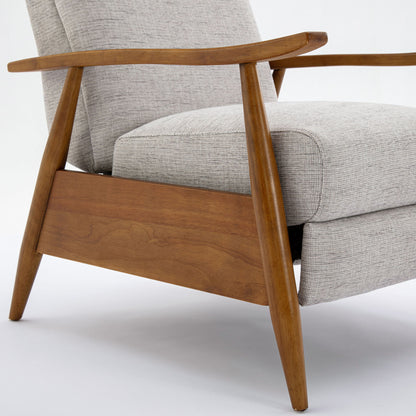 A close-up of the Vaughn Push Back Recliner, featuring light gray fabric cushions and an angled solid hardwood frame and armrests, set against a white background.