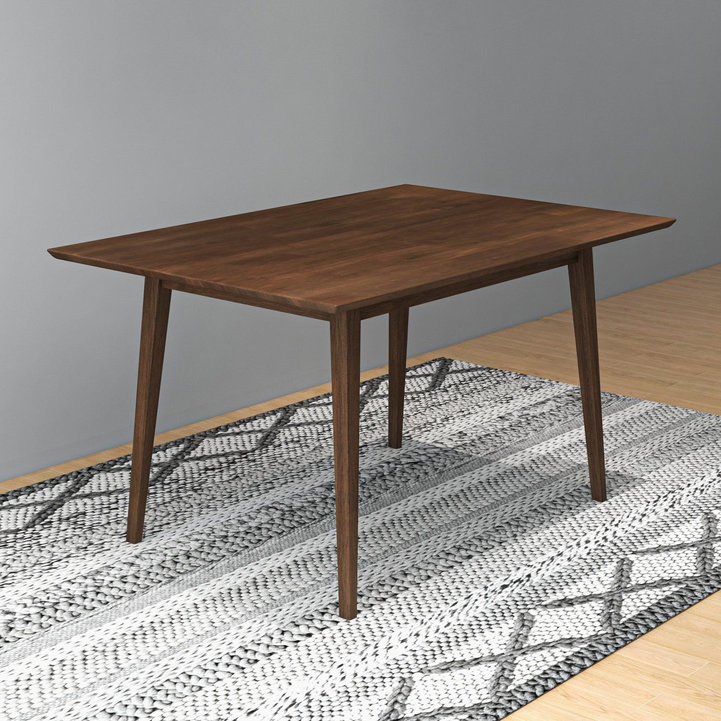 The Carlos Dining Table with angled legs stands on a patterned rug in a room featuring light wood flooring and gray walls.