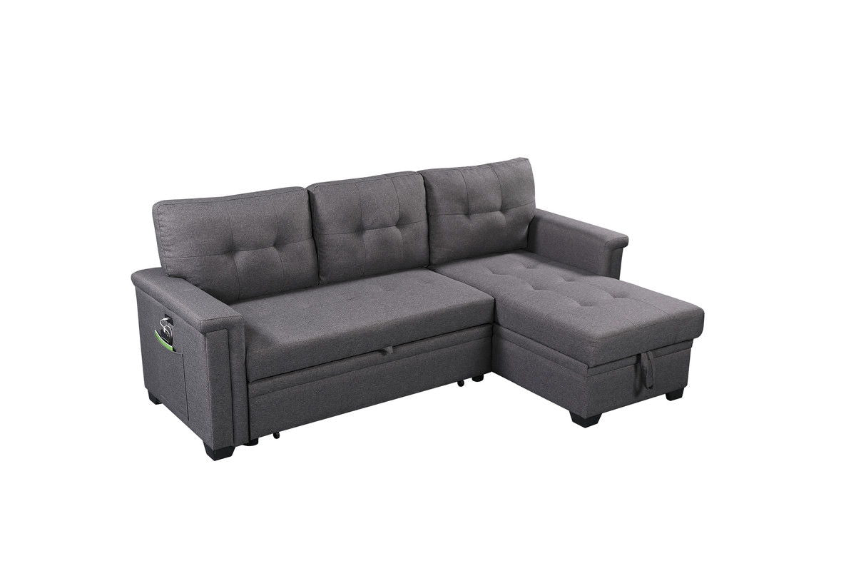 The Nathan Reversible Sleeper Sectional Sofa features a dark gray design with a storage chaise, tufted cushions, USB charging ports, and a left armrest pocket, shown against a white background.