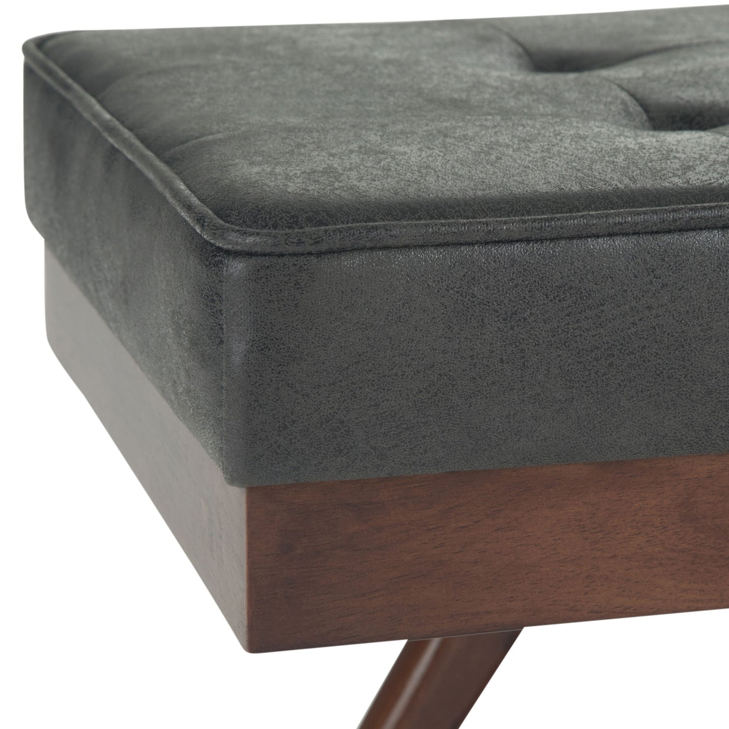 Close-up of the Pierce - Mid Century Upholstered Ottoman Bench showing a tufted, dark gray cushion and wooden frame with angled legs.
