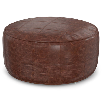 The Connor - Handcrafted Round Pouf features brown leather with visible grid stitching and a slightly distressed texture for a rustic look.
