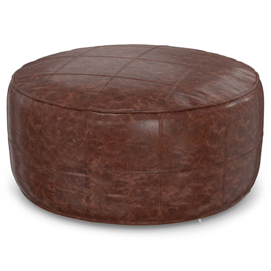 The Connor - Handcrafted Round Pouf features brown leather with visible grid stitching and a slightly distressed texture for a rustic look.