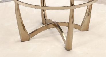 Close-up of the gold metallic base with four curved legs on a light floor, part of the Orlando - Clear Glass Coffee Table in Champagne finish. The tabletop is not shown.
