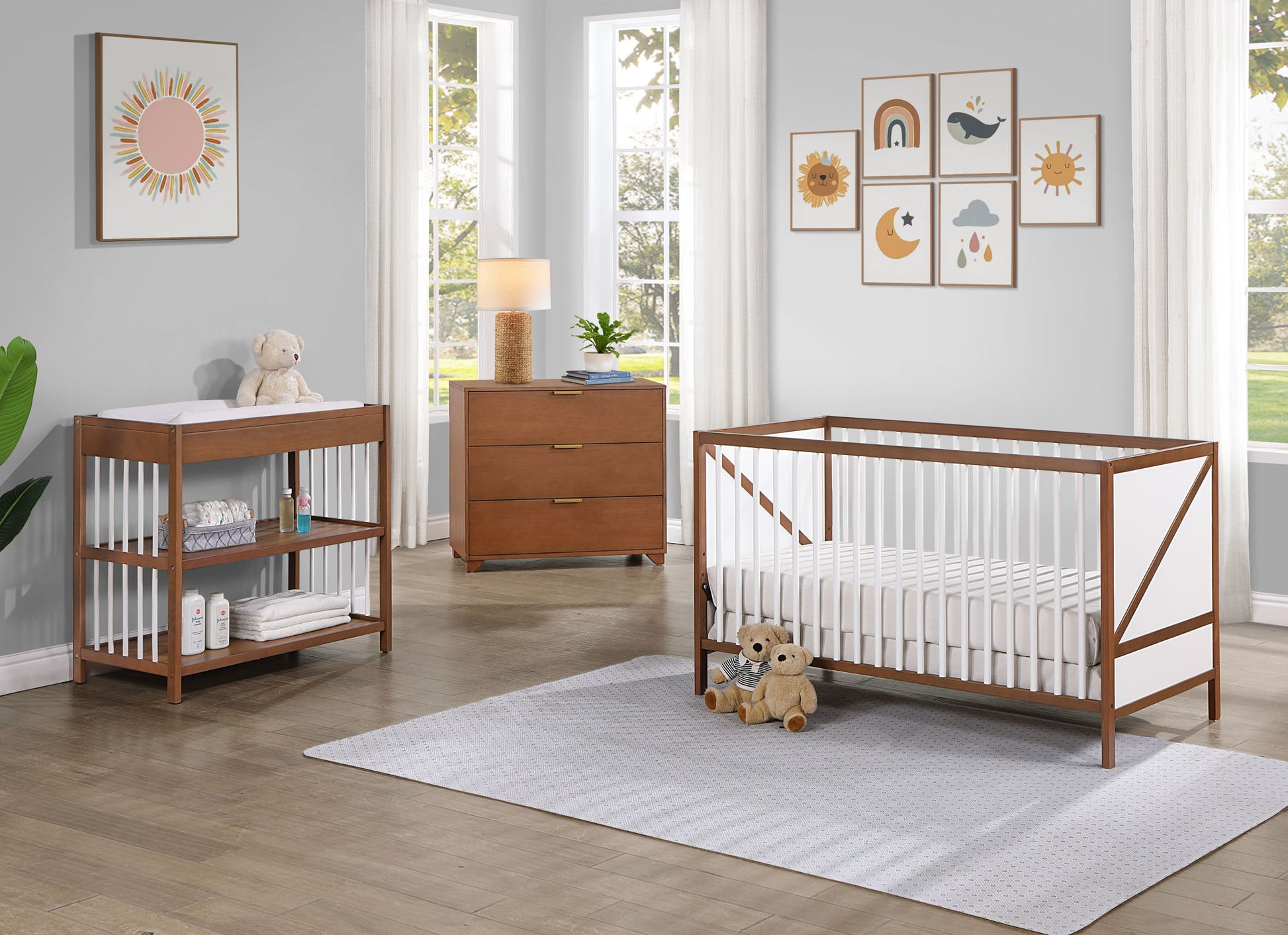 Modern nursery with the Pixie Zen 3-in-1 Crib in walnut, matching furniture, a soft rug, plush toys, baby essentials, and art prints of suns, rainbows, and animals. Large windows reveal trees and fill the room with natural light.