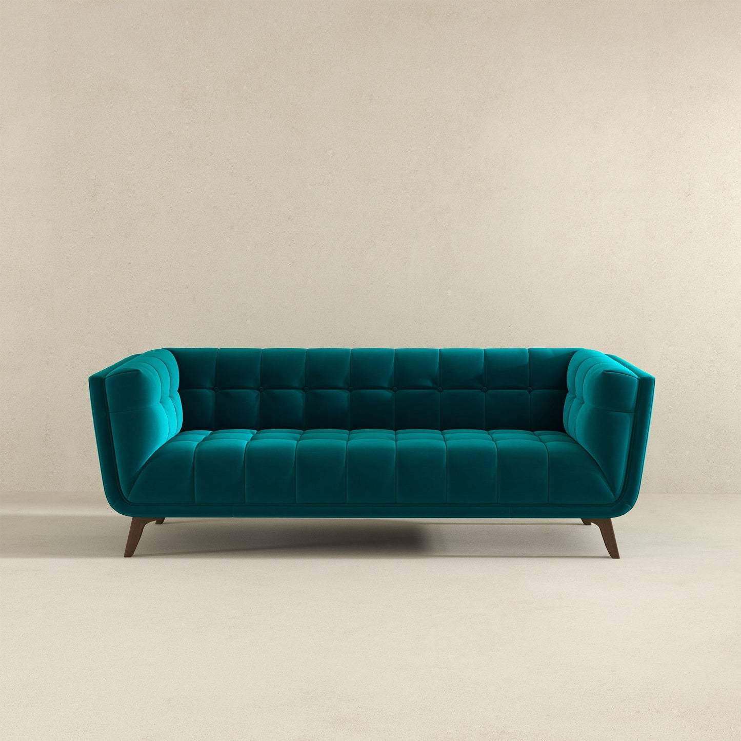 The Addison Mid-Century Modern Design Tufted Sofa, in teal velvet with tufted cushions and angled wooden legs, is set against a plain beige wall and a light floor.