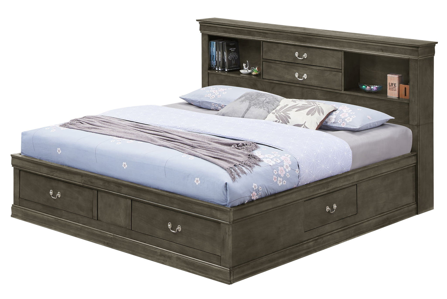 The Louis Phillipe Bookcase Storage Bed features storage drawers in the base and headboard, topped with a light blue floral comforter, gray blanket, and pillows. The headboard displays books, a clock, and small decor pieces.