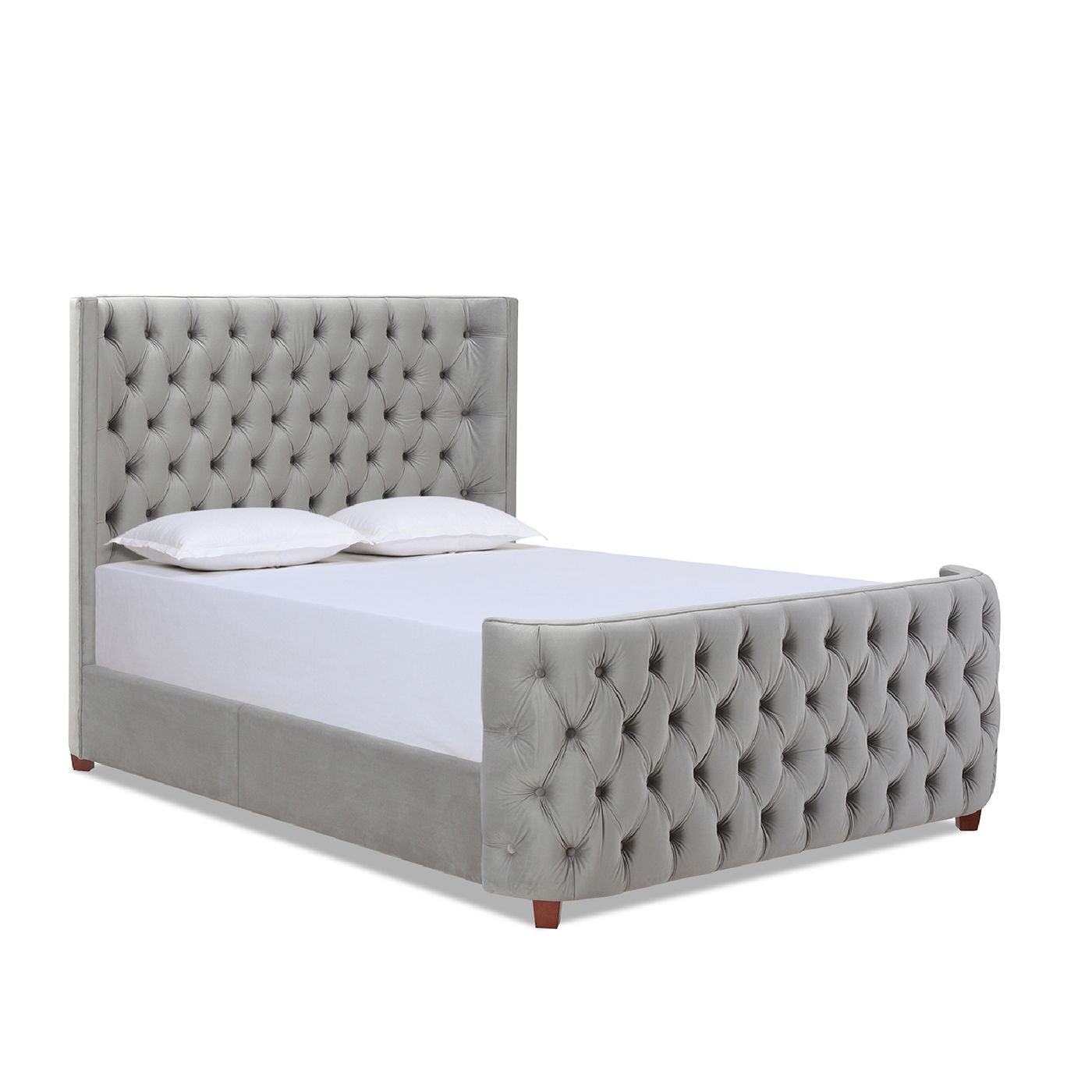The Brooklyn Tufted Panel Bed Headboard And Footboard Set features a gray upholstered frame, tufted headboard and footboard, two white pillows, a white mattress, and stands on short wooden legs.