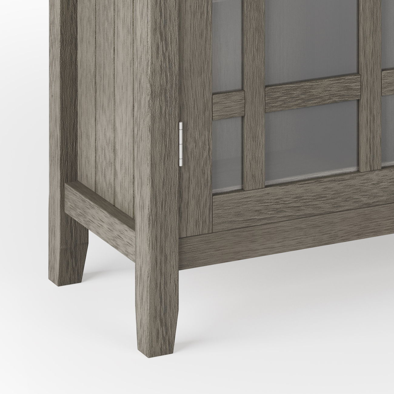 Close-up of the bottom corner of the Bedford - Storage Media Cabinet, featuring gray wood, glass panel doors, and simple straight legs.