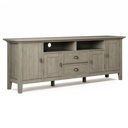 The Redmond Handcrafted TV Media Stand is a long, light gray wooden piece with four doors, two central drawers, two open shelves, a rear cable management hole, and dark round and cup-style handles.