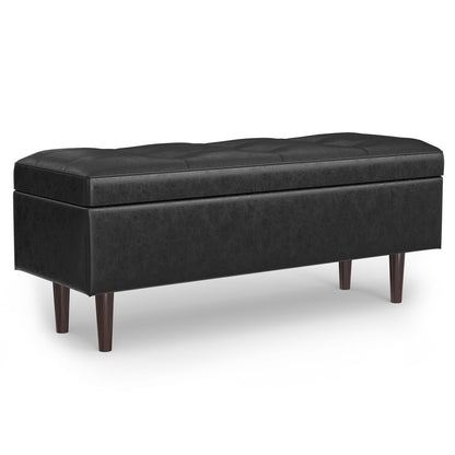 The Shay Large Square Coffee Table Storage Ottoman features black upholstery, a tufted top, and four dark wood legs in a mid-century style, displayed against a white background.