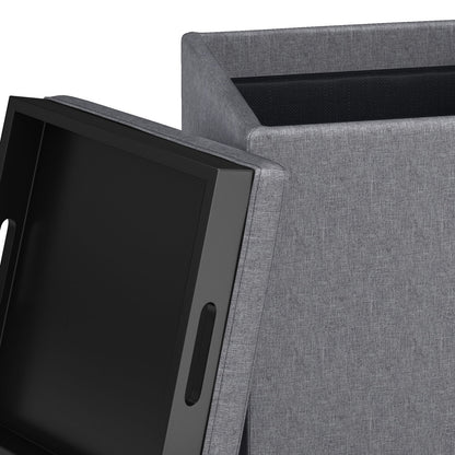 A close-up of the Rockwood Upholstered Cube Storage Ottoman With Tray, shown in gray fabric with its lid off, displaying a black handled tray inside.