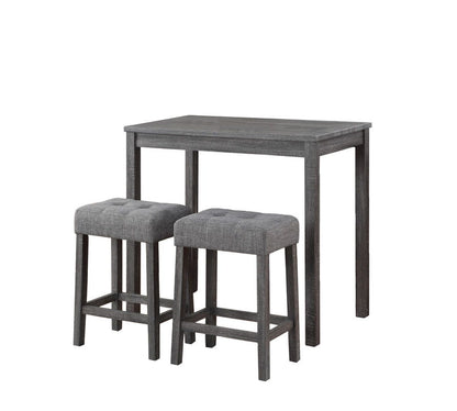 The Lux 3 Piece Counter Height Pub Table set includes a small rectangular wooden table with a dark gray finish and two matching tufted linen upholstered stools with cushioned seats.