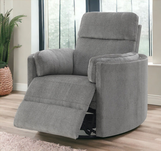 The Sagen Chenille Glider Recliner With Swivel, featuring an extended footrest, sits on a wooden floor near a large window, accompanied by a potted plant and woven basket.