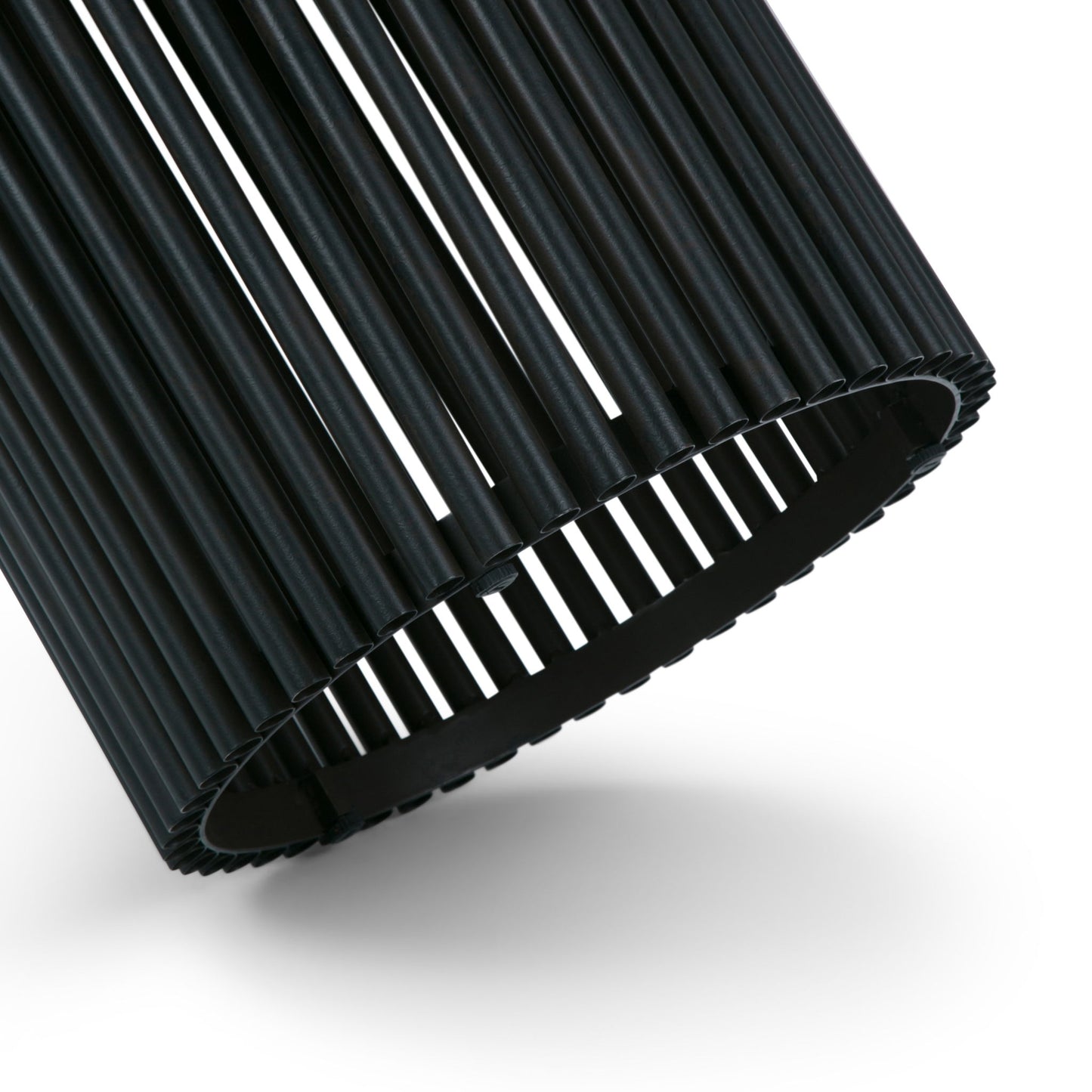 A close-up of the Demy Accent Table in natural and black, featuring a cylindrical design with evenly spaced vertical slats. Light passes through the gaps, creating a striking striped effect against a white background.