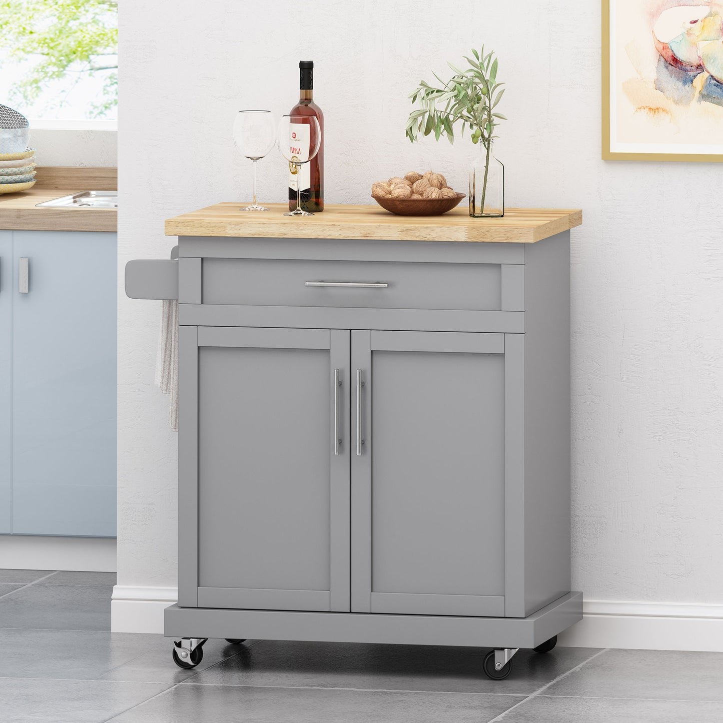 The Negley Contemporary Kitchen Cart With Wheels in gray features a wooden top, two doors, a drawer, a towel rack, and four wheels—perfect for storing kitchen items or serving drinks and snacks.
