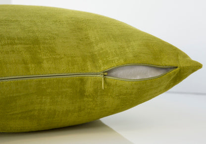 A close-up of the green Pillow Square, Insert Included, Decorative Throw, Hypoallergenic shows a partially open zipper revealing the white inner lining.