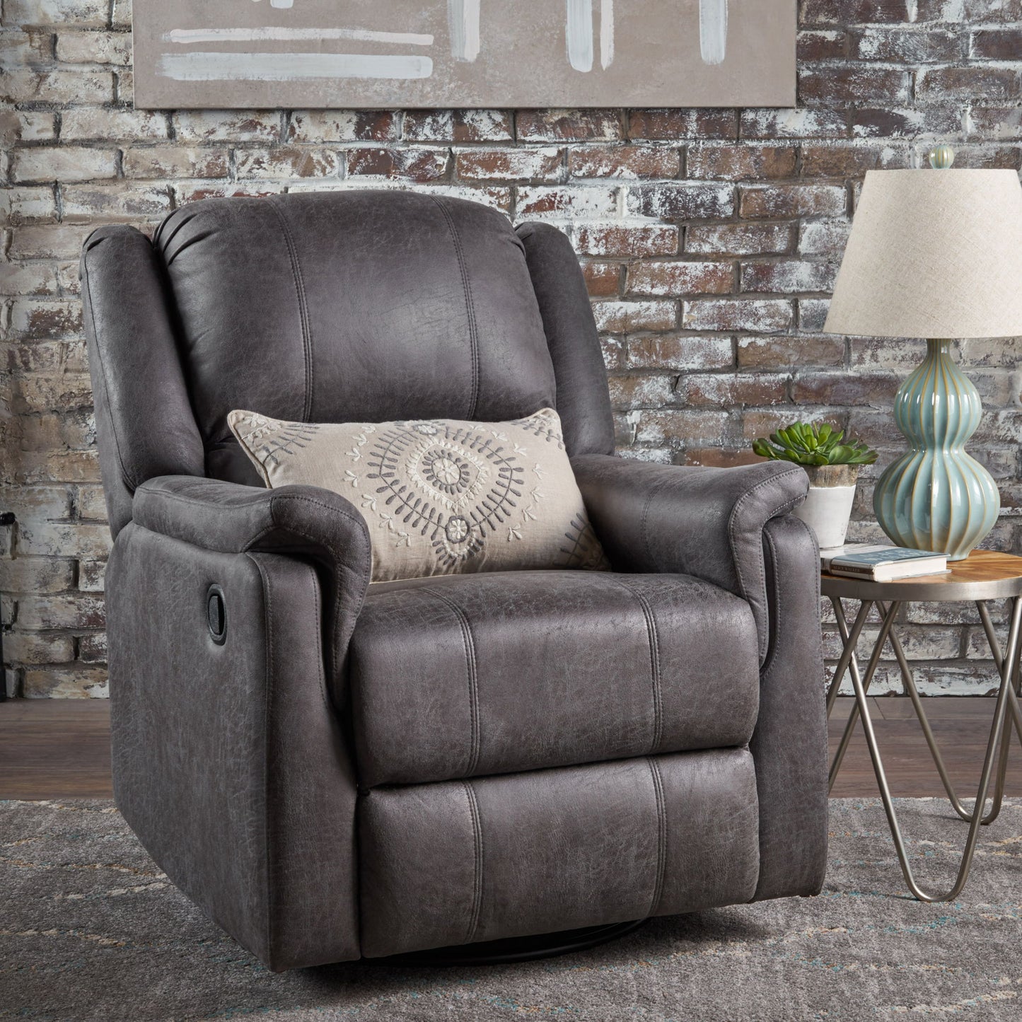 A Contemporary Glider Recliner With Swivel Function, featuring a patterned cushion, sits on a rug before a rustic brick wall. Beside it is a small round table topped with a striped lamp and potted plant.