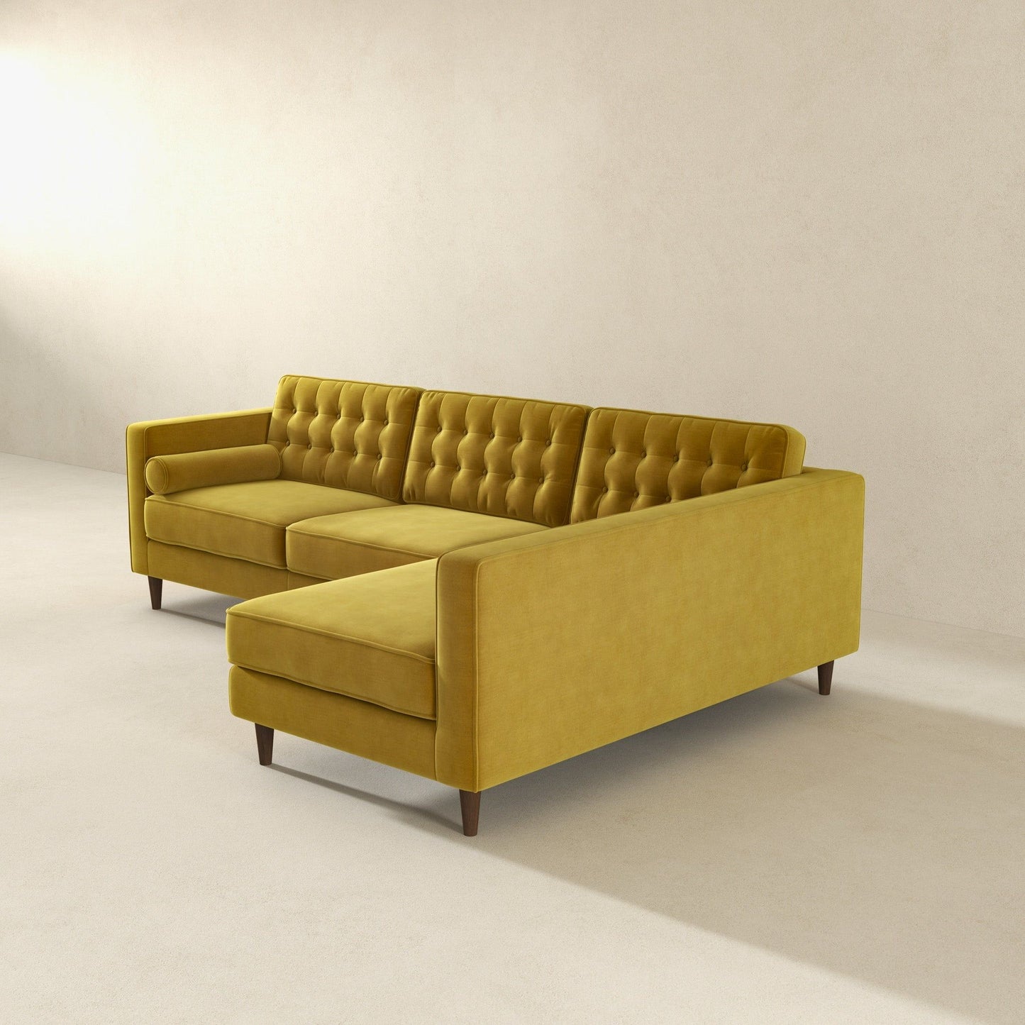 The Christian Mid-Century Modern Design Sectional Sofa in mustard yellow, featuring tufted upholstery and an L-shaped chaise on wooden legs, stands out in a minimalist, light-toned room with simple walls and flooring.