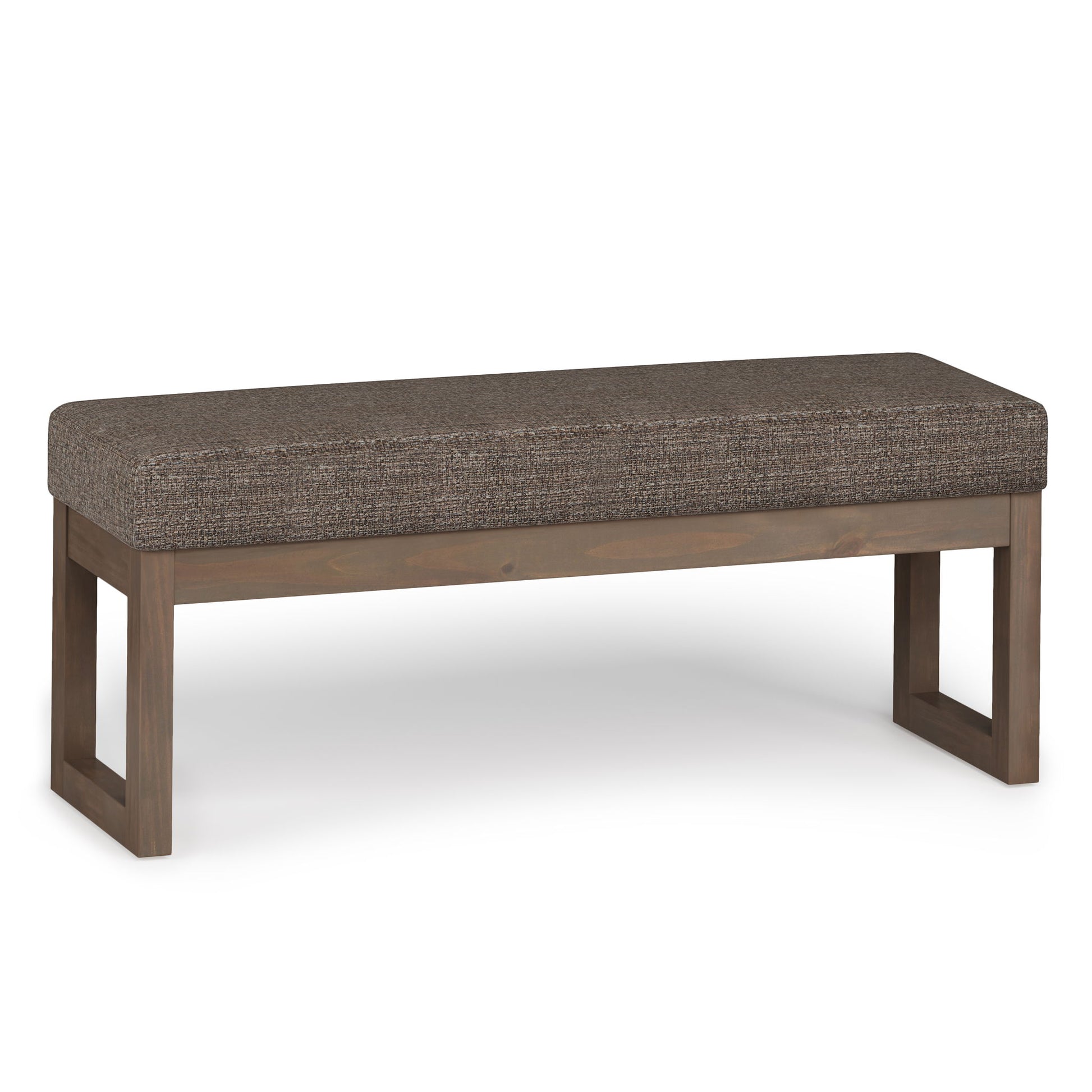 The Milltown - Upholstered Ottoman Bench features a rectangular wooden open-frame base and a cushioned seat in textured brown fabric, displayed against a plain white background.
