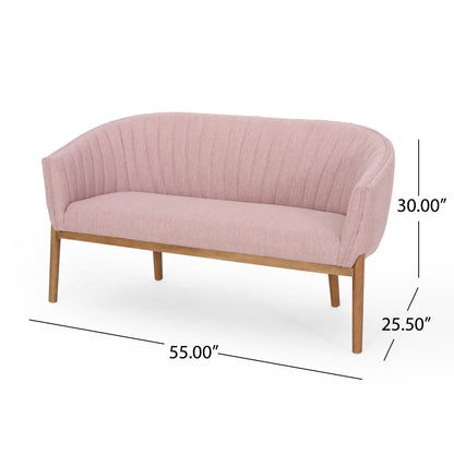 The Mid Century Modern Loveseat With Channel Stitched Backrest features pink upholstery, wooden legs, a curved back, and horizontal channel stitching. Dimensions: 55" W x 30" H x 25.5" D.