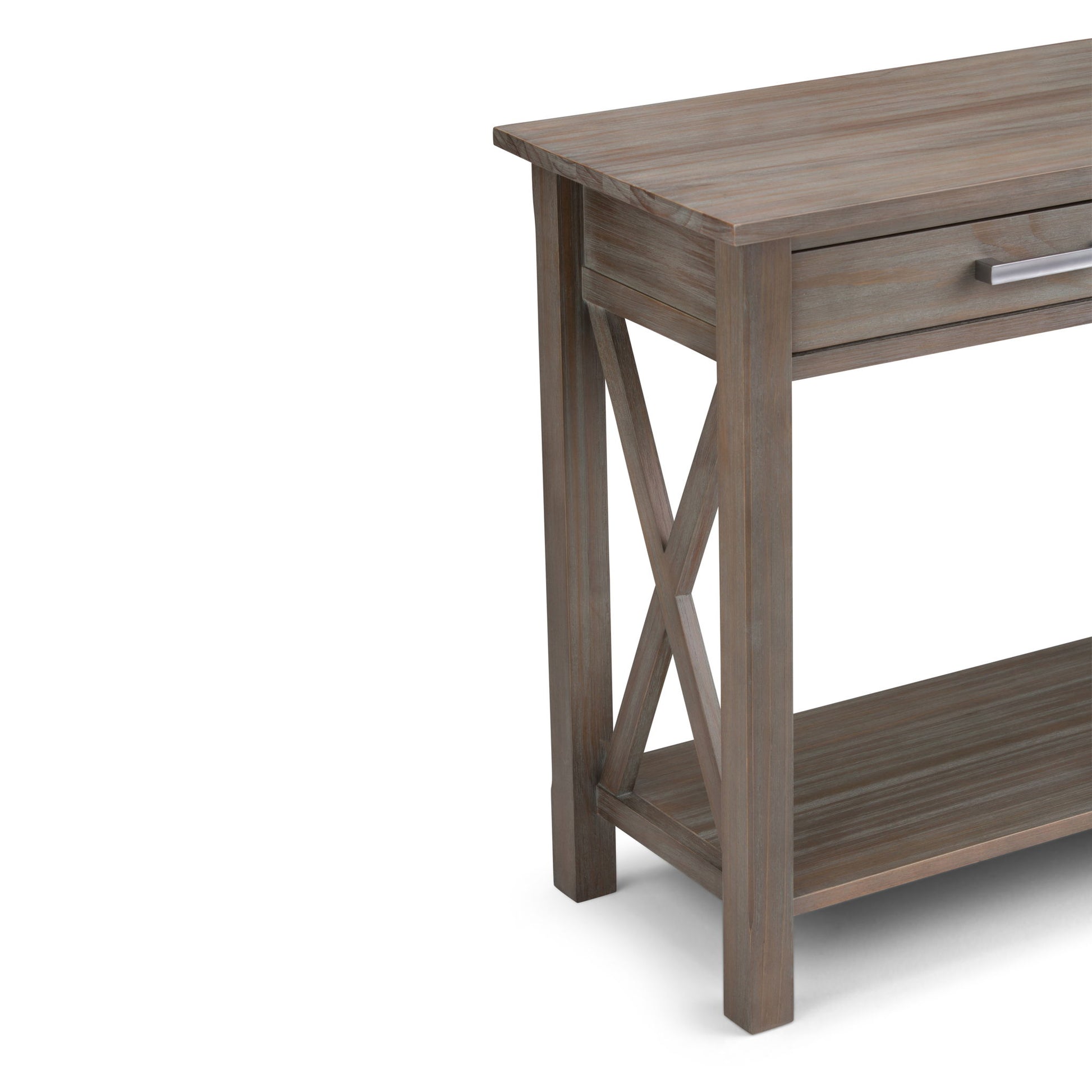 Partially visible, the Kitchener - Handcrafted Table features a weathered wood finish, X-shaped side supports, a lower shelf, and a drawer with a silver handle.